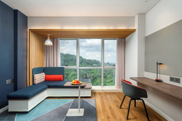 Una sala moderna con un sofá seccional, una mesa de comedor y un amplio ventanal con vistas a zonas verdes.