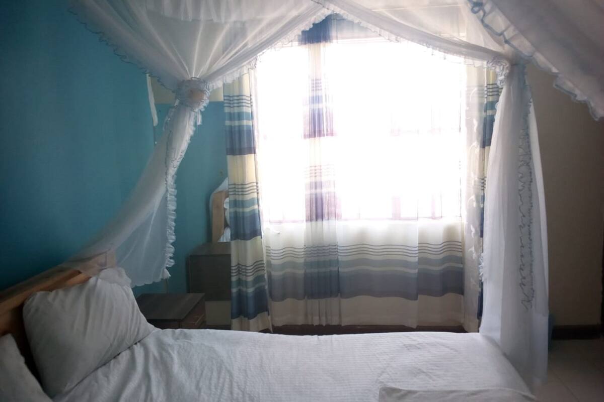 A bedroom with a bed, curtains, and a window.