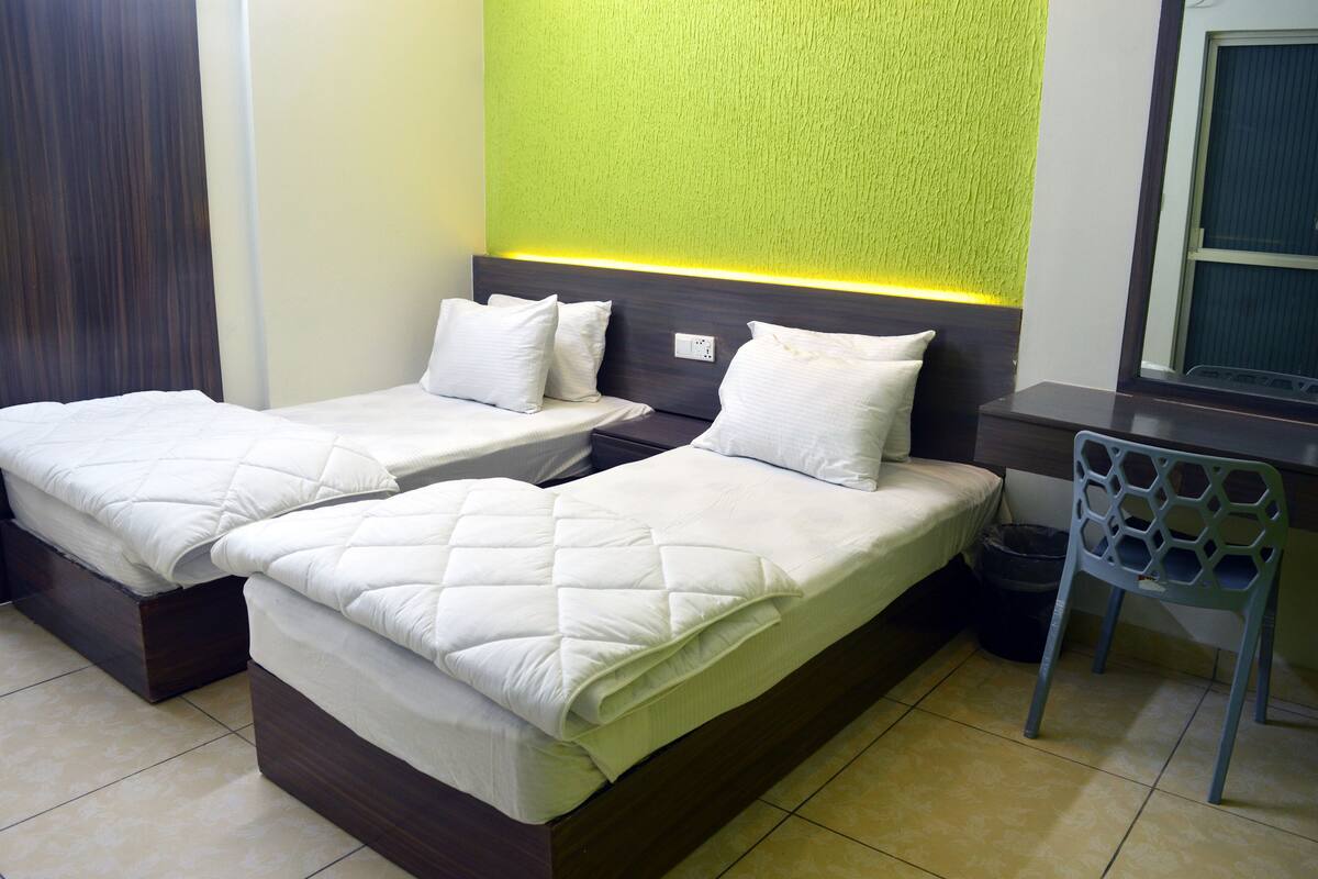 Une chambre d’hôtel avec deux lits, un bureau et une chaise.