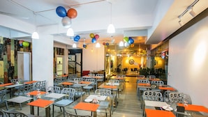 Un espace repas avec plusieurs tables et chaises, un éclairage au plafond et des ballons de couleurs vives.