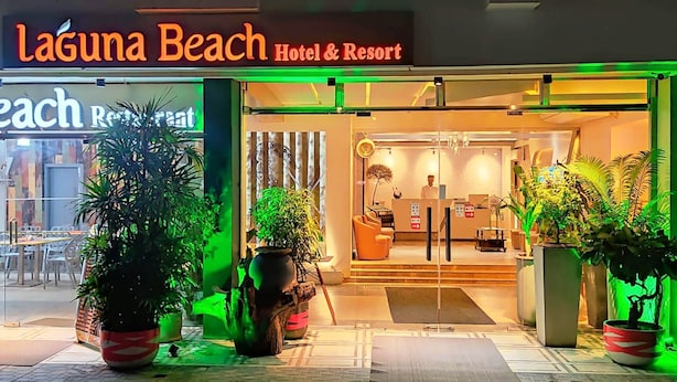 L’extérieur de l’hôtel et du complexe Laguna Beach, avec une enseigne indiquant un menu thaïlandais, des plantes en pot et une entrée bien éclairée.