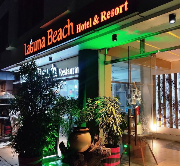 Exterior del Hotel & Resort Laguna Beach con un letrero de restaurante, plantas en macetas y una entrada de vidrio.
