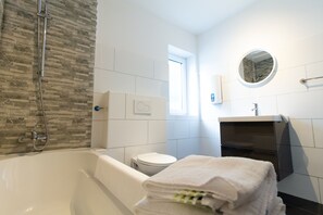 Ein modernes Badezimmer mit Badewanne, Toilette und Spiegel.
