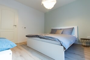 Ein Schlafzimmer mit Bett, Nachttisch, Lampe und Tür.