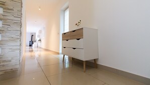 A modern hallway with a white dresser, stone wall, and a view into another room. - T & T Suites Raunheim (Raunheim)