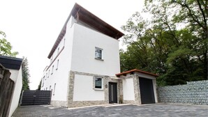 A modern two-story building with a white facade and stone accents, a gated driveway, and a stone wall. - T & T Suites Raunheim (Raunheim)