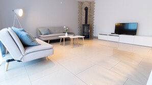 A modern living room with a sofa, a coffee table, a TV, and a stone fireplace. - T & T Suites Raunheim (Raunheim)