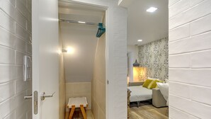 Un baño con ducha, un taburete de madera y un perchero para toallas.