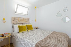 A bedroom with a bed, a bedside table, a window, and wall decorations.