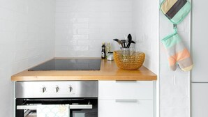 Una cocina con encimera de madera, horno de acero inoxidable y salpicadero de azulejos blancos.