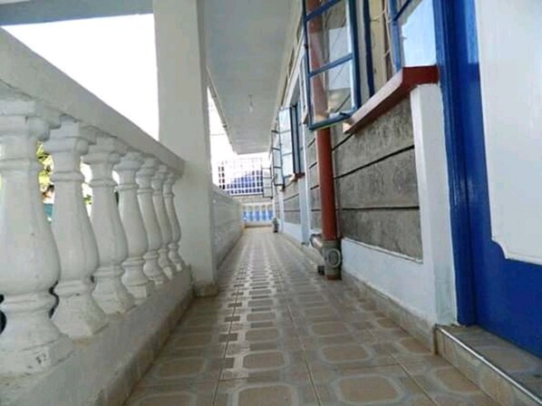 Un pasillo con piso estampado, barandillas blancas y una pared azul con una tubería roja.