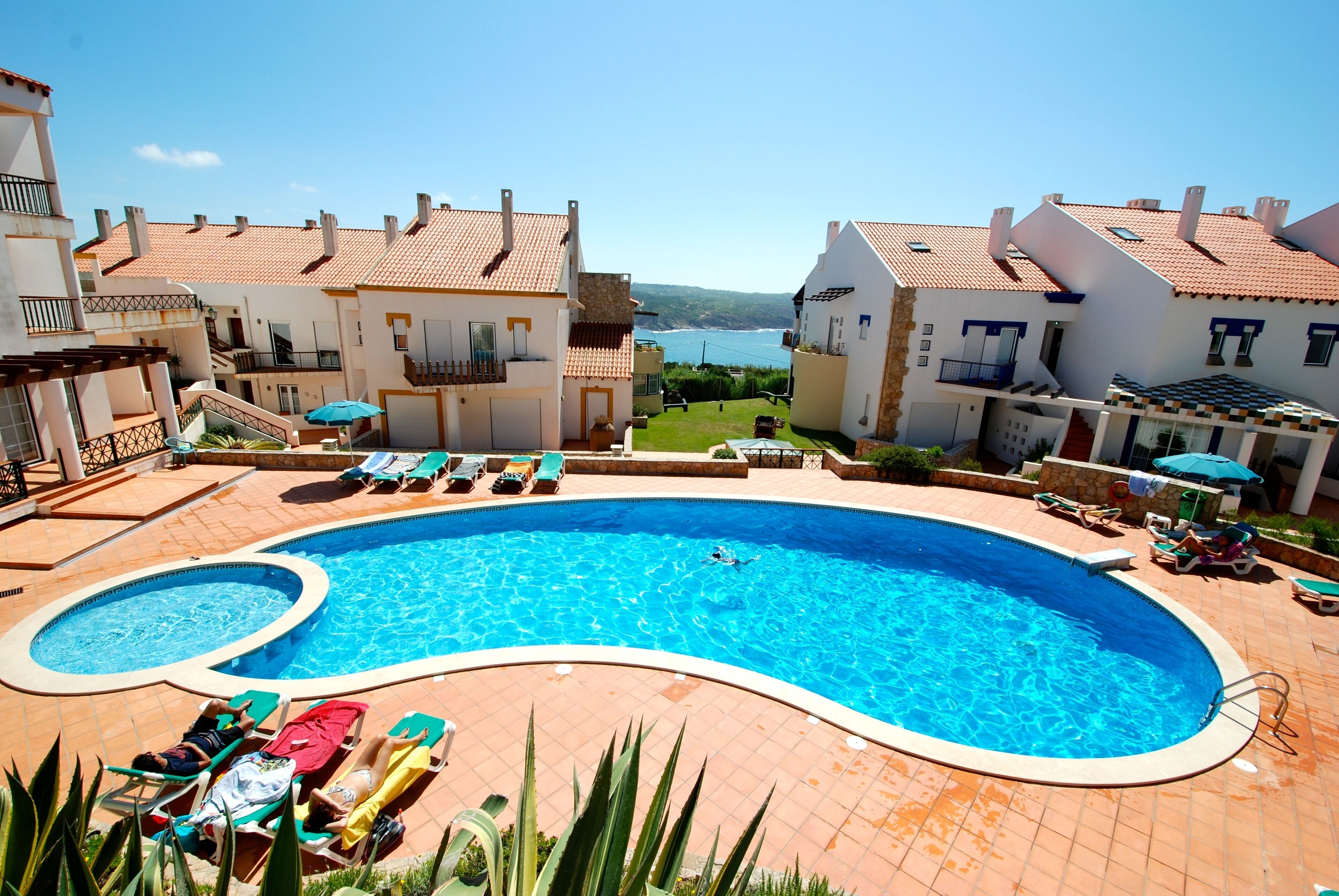 A swimming pool surrounded by lounge chairs and a view of the sea.