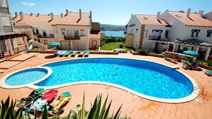 A swimming pool surrounded by lounge chairs and a view of the sea.