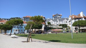 A paved walkway with benches, a grassy area, and buildings with varied architecture in the background.