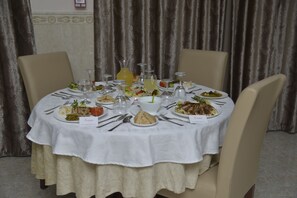 A round dining table set for a meal with various dishes, glasses, and cutlery. - Hotel Amsterdam (Algiers)