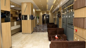 A hotel lobby with a reception desk, seating area, and lockers. - Hotel Amsterdam (Algiers)