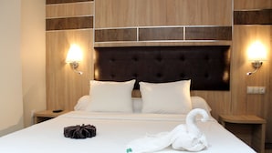 A neatly made bed with white linens and pillows, a dark headboard, and two bedside tables with lamps. - Hotel Amsterdam (Algiers)