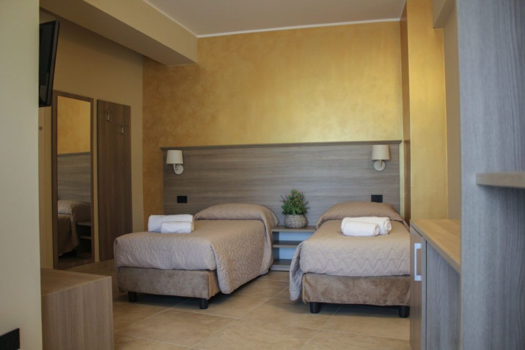 Habitación de hotel con dos camas, una mesita y un espejo.