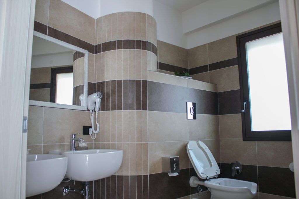 Une salle de bain avec deux lavabos, des toilettes et un miroir.