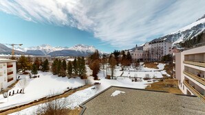Un hotel con vistas a montañas nevadas, un patio con árboles y una zona de grava.