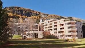 Un hotel de varios pisos con balcones, un patio central y un paisaje montañoso al fondo.