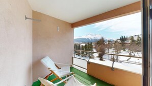 Un balcón con vista a una montaña nevada y un pueblo.