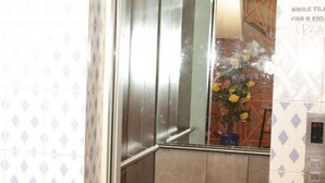 A bathroom with a mirror, a towel rack, and a tiled wall with a diamond pattern. - Maina Highway Hotel (Embu)