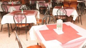 A restaurant with multiple tables and chairs, each covered with a white tablecloth and a red placemat. - Maina Highway Hotel (Embu)