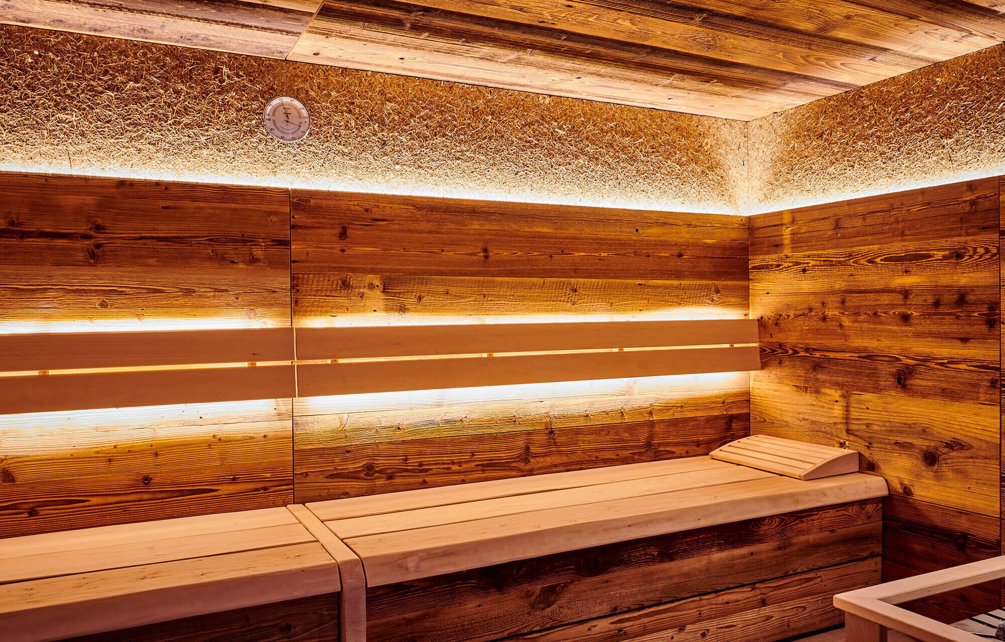 A wooden sauna with benches and a visible temperature gauge.