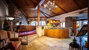 A cozy lobby with a wooden reception desk, a staircase, and a chandelier. - Posthotel Rattenberg (Rattenberg)