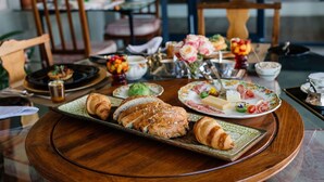 A breakfast setting with croissants, cheese, and various fruits on a wooden table. - Vineyard Views Country House (Riebeek Kasteel)