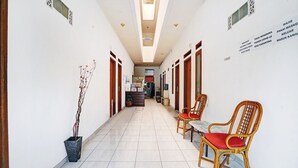 Un couloir d’hôtel avec un comptoir d’accueil, des chaises et une plante en pot.