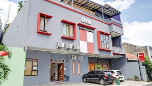 Un bâtiment portant le nom « OYO » en lettres bien visibles, doté d’une architecture moderne avec un toit plat et un balcon.