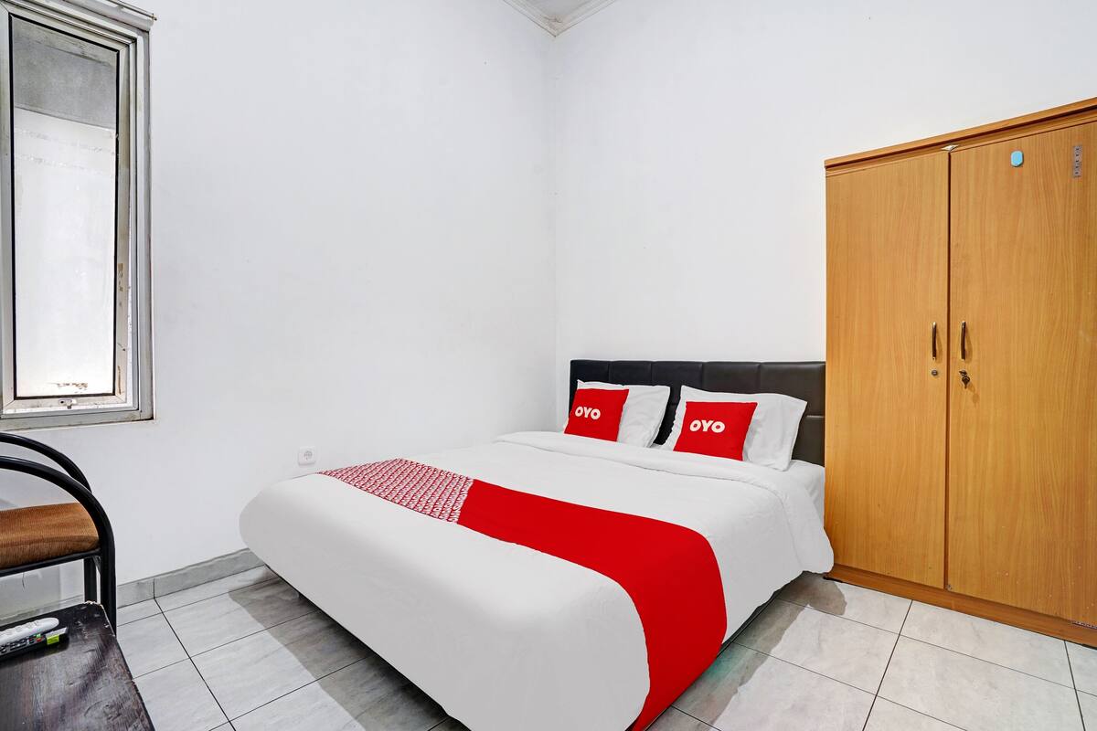 Een slaapkamer met een bed, een kledingkast, een stoel en een raam.