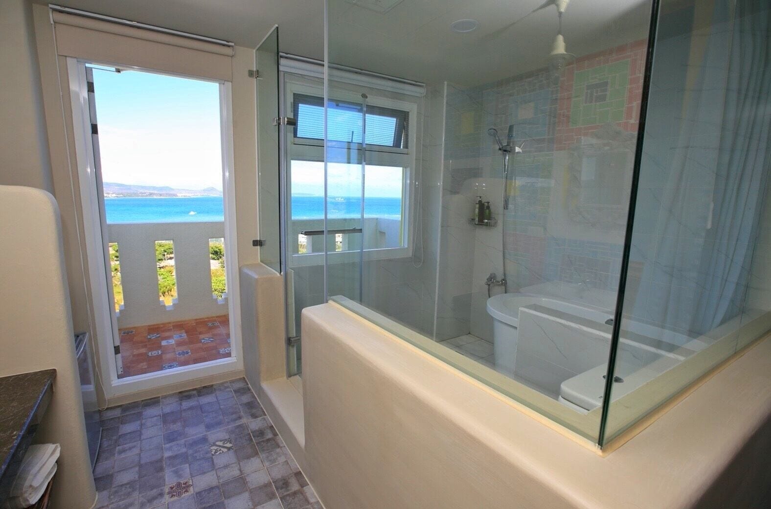 A bathroom with a glass-enclosed shower, a toilet, and a sink.
