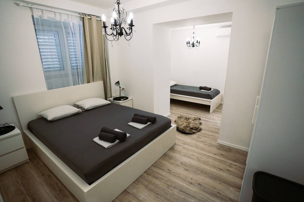 Un dormitorio moderno con una cama grande, una mesita de noche y una mesita auxiliar con una lámpara.