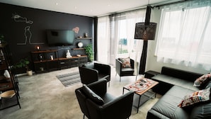 A modern living room with a sofa set, a coffee table, and a TV. There are plants and decorative items on shelves. - Villa Marghareta 2 (Dubrovnik)