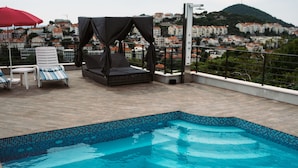 A rooftop pool with clear blue water, lounge chairs, and a canopy. - Villa Marghareta 2 (Dubrovnik)