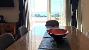 A hotel room with a dining table, chairs, a red bowl, a wooden cabinet, and a TV on the wall. - Villa Marghareta 2 (Dubrovnik)