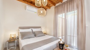 Ein Schlafzimmer mit einem Bett, Nachttischlampen, einem hölzernen Nachttisch, einem Tisch mit einer Champagnerflasche und einem Fenster mit Vorhängen.