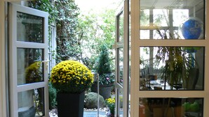 Una puerta que da a un jardín con una maceta amarilla grande y diversas plantas.