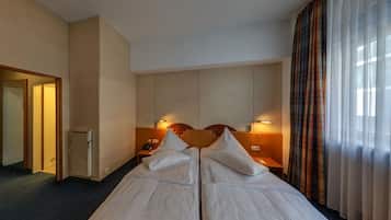 Una habitación de hotel con dos camas, un escritorio pequeño, un espejo y un armario.