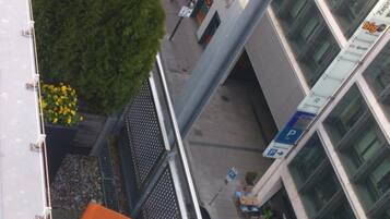 Un edificio a più piani con terrazza sul tetto, area salotto all'aperto e percorso pedonale.
