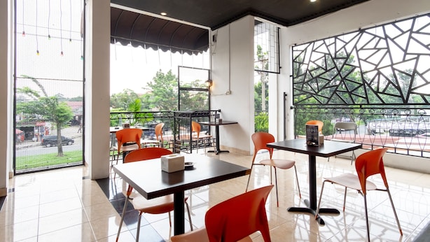 Un café moderno con mesas y sillas, ventanas amplias y vistas al exterior.