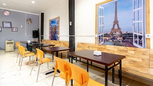 Un comedor con mesas y sillas, un cuadro grande de la Torre Eiffel y una pared de madera.