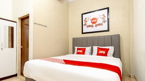 Una habitación de hotel con una cama, una puerta, un cuadro en la pared y una colcha roja y blanca.