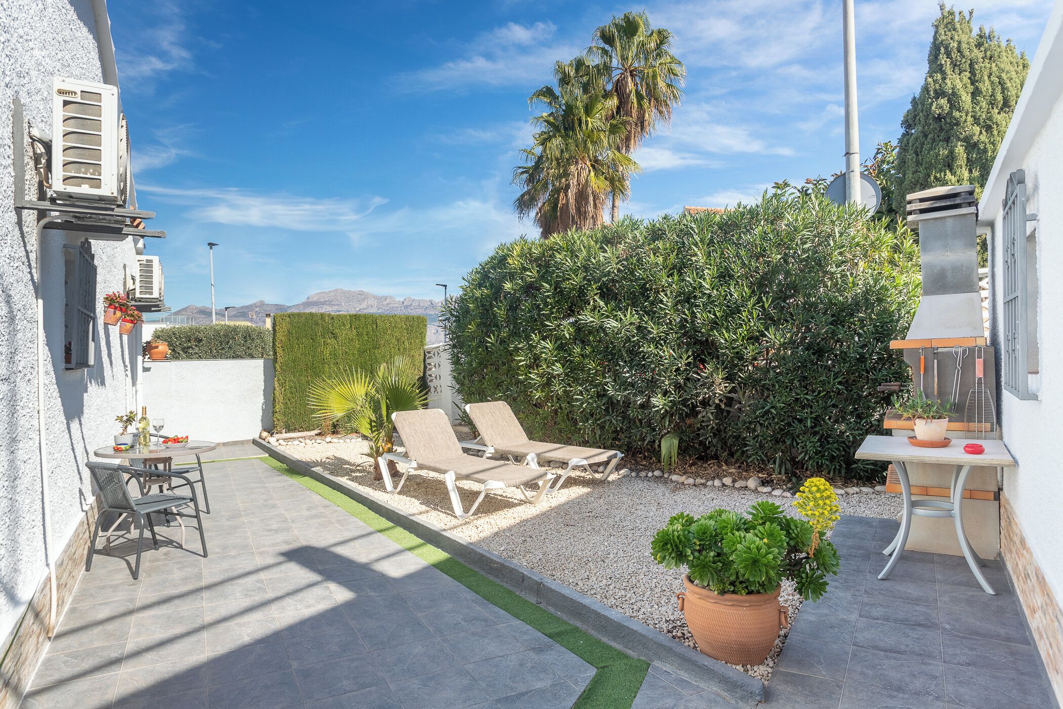 Patio exterior con barbacoa, tumbonas y mucho sol