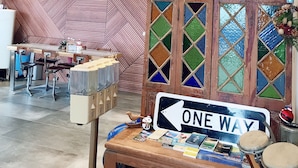 A modern interior with a staircase, a 'ONE WAY' sign, a wooden table with magazines and a drum set, and a patterned wall. - One Way B&B (Hualien City)