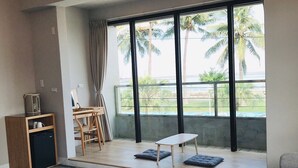 A modern living room with a large window, a wooden desk, a sofa, and a coffee table. - One Way B&B (Hualien City)