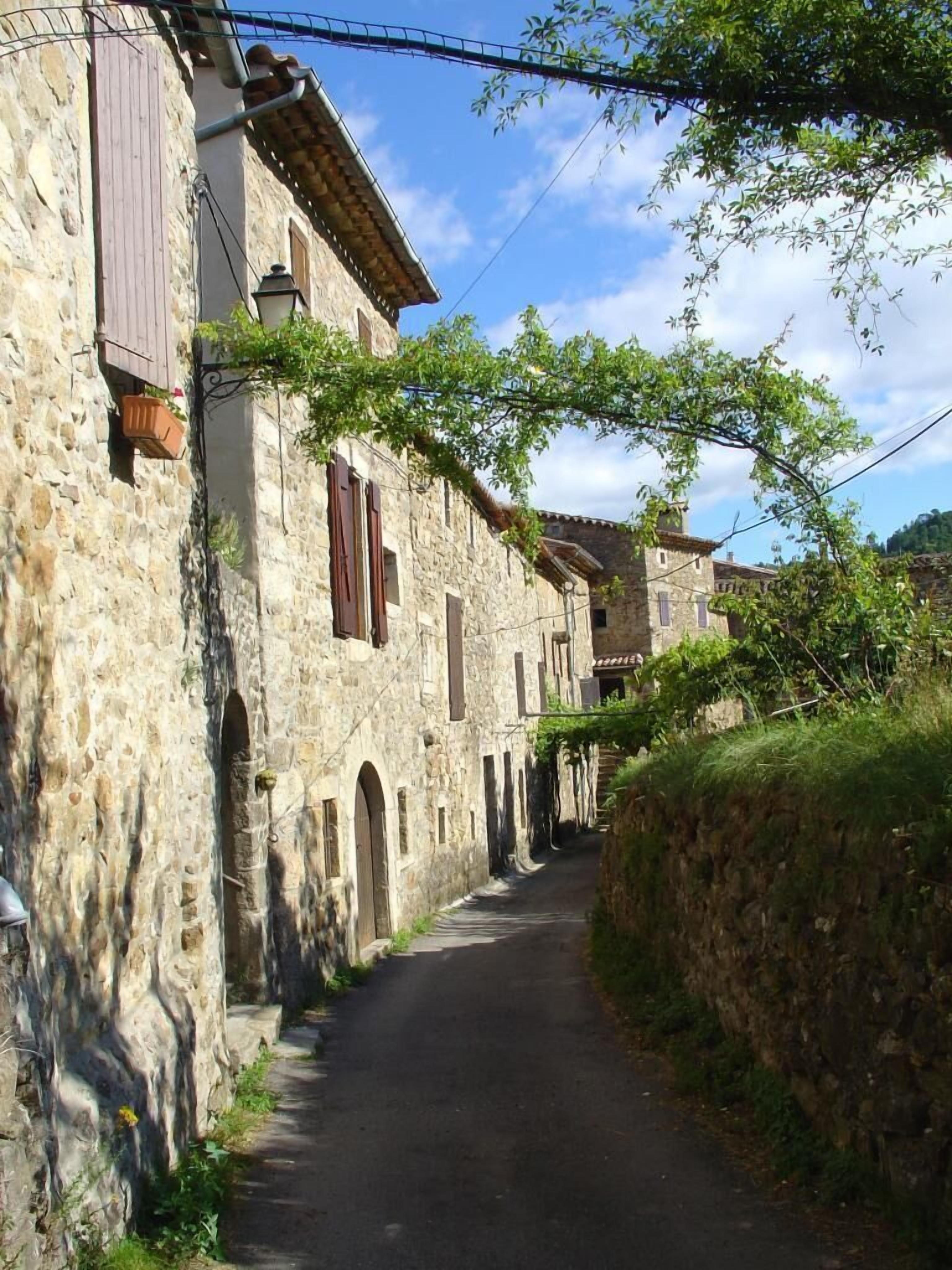 Eine enge Gasse, gesäumt von traditionellen Steinhäusern mit Rundbögen und Holzhörnern.